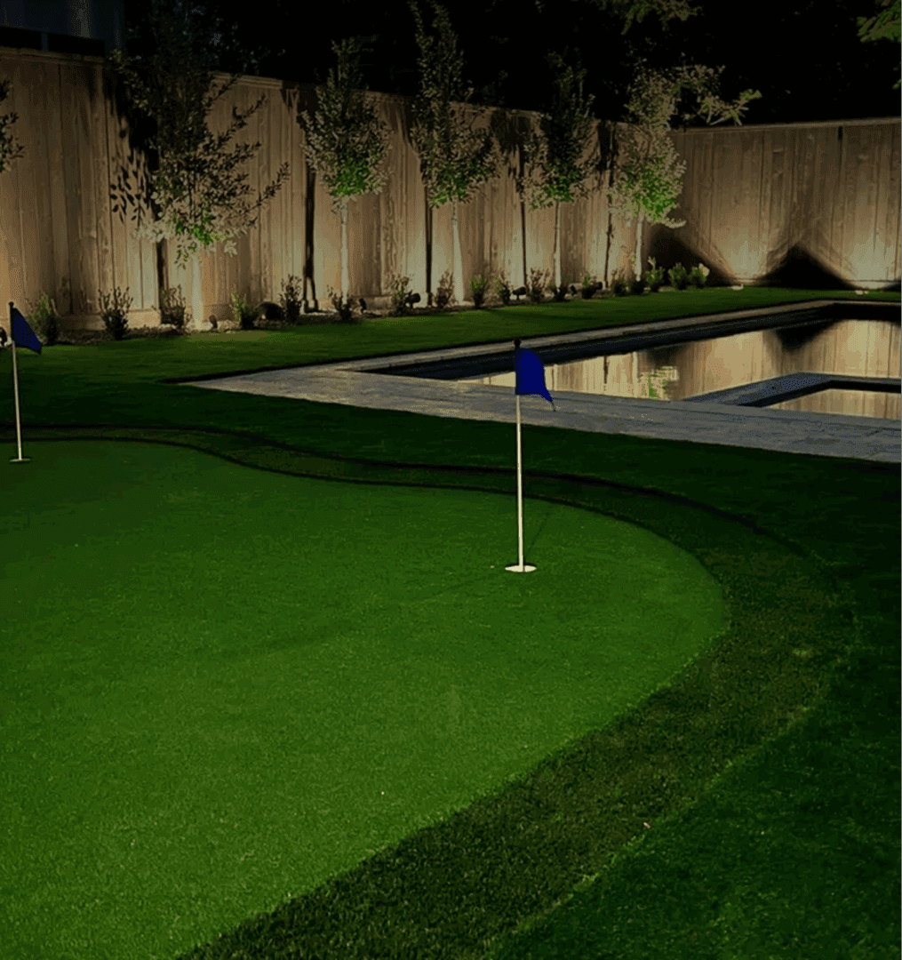 Backyard with putting green and pool at night.