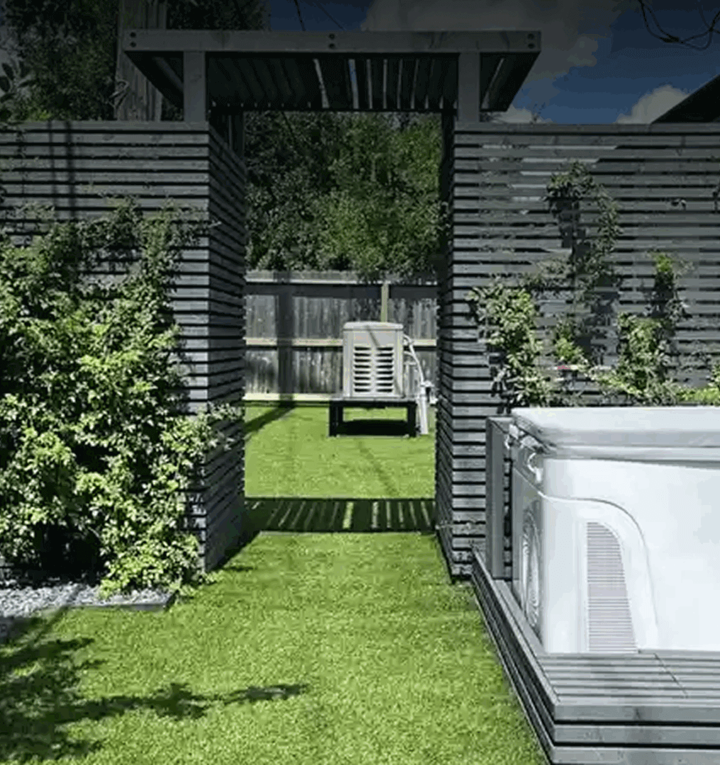 Garden with wooden pergola and hot tub.