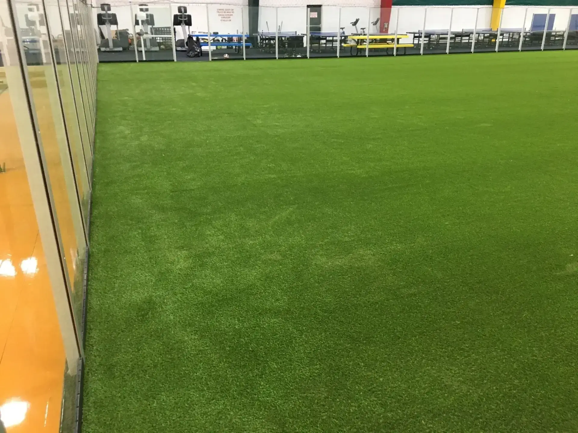 Indoor artificial turf field with glass wall.
