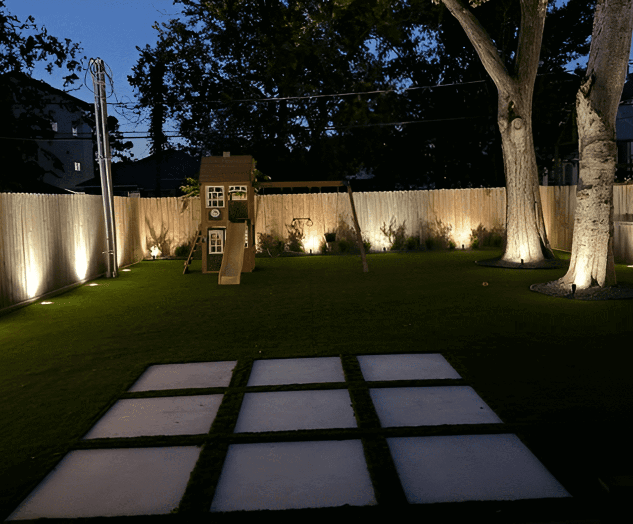Backyard playground illuminated at night.