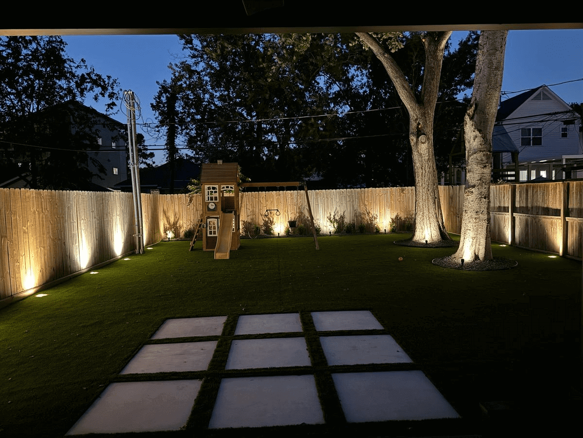 Backyard playground with evening lights illuminated.