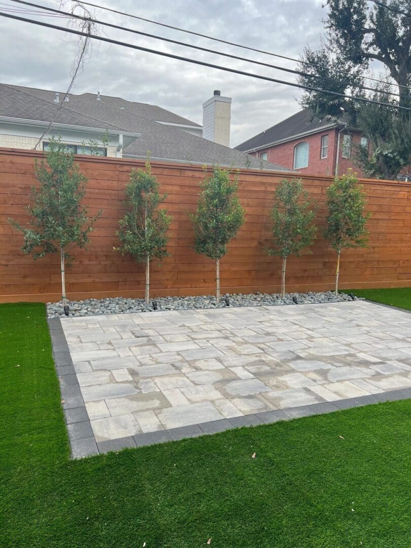 Backyard patio with trees and wooden fence.