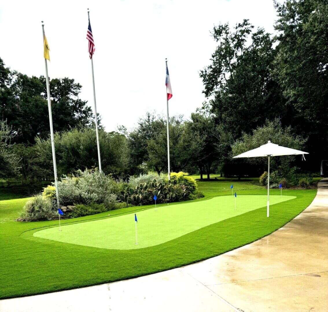 Putting green with flags and umbrella shade.