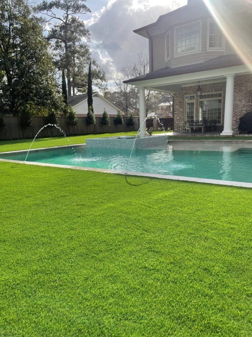Backyard with pool and green lawn.
