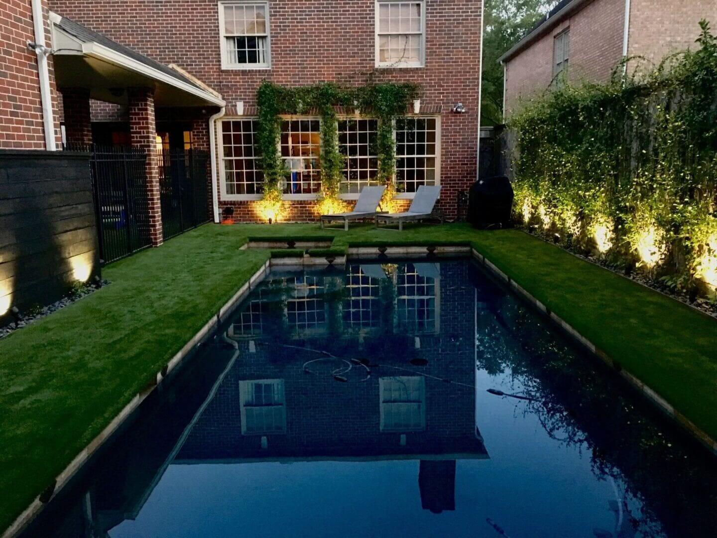 Brick house with illuminated backyard pool.