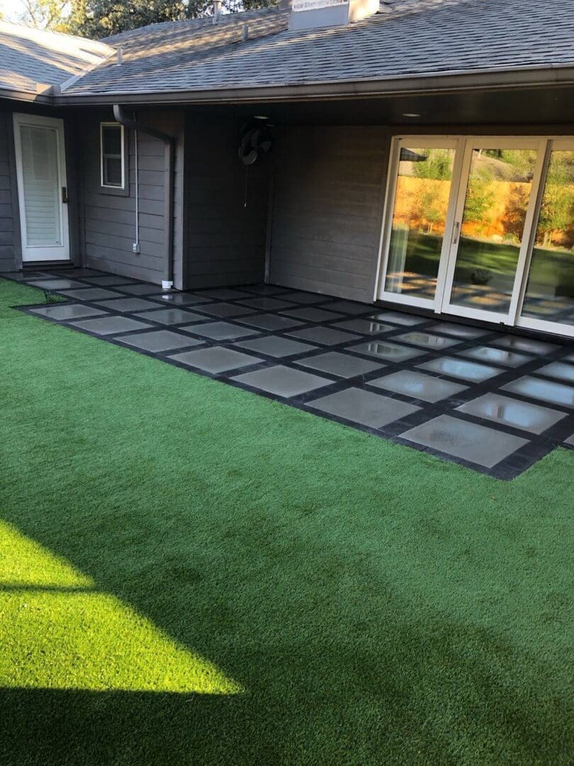 Modern backyard patio with artificial grass and stone tile design.