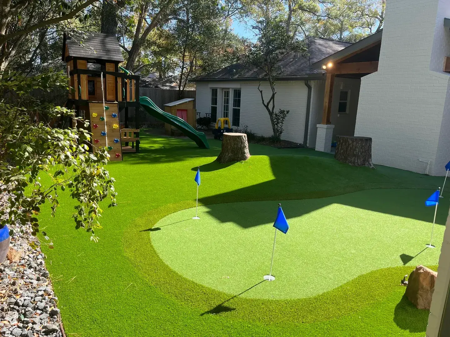 Small backyard putting green with flags and slide.
