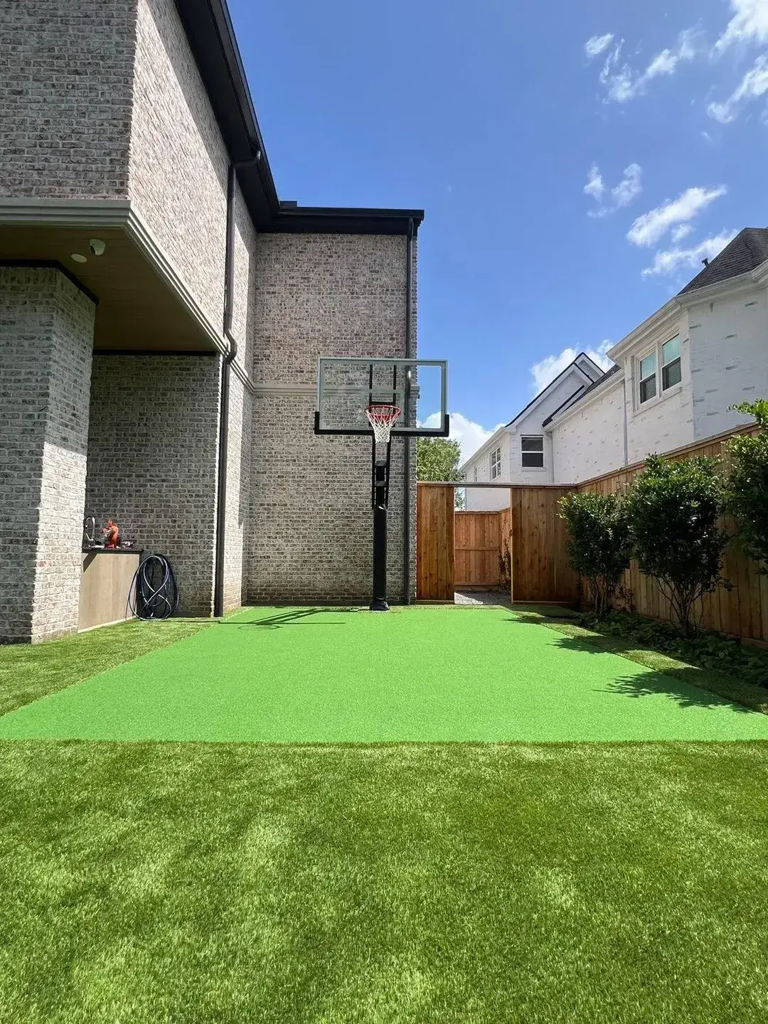 Backyard basketball hoop with green turf on a sunny day.