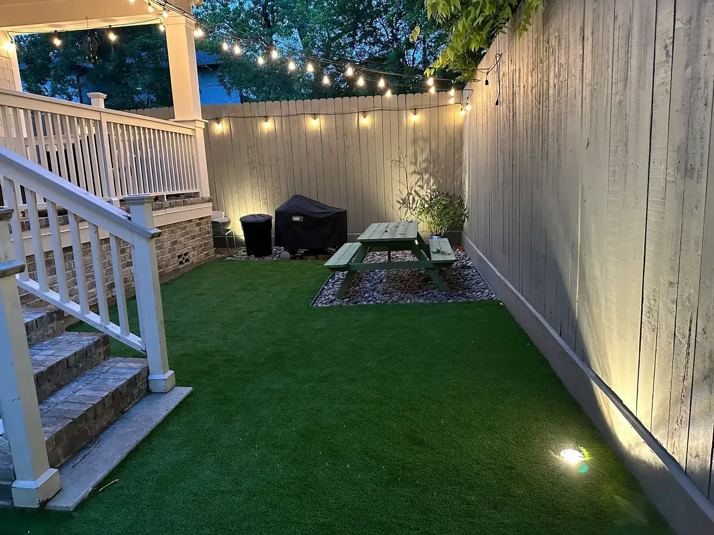Cozy backyard with string lights and artificial turf.